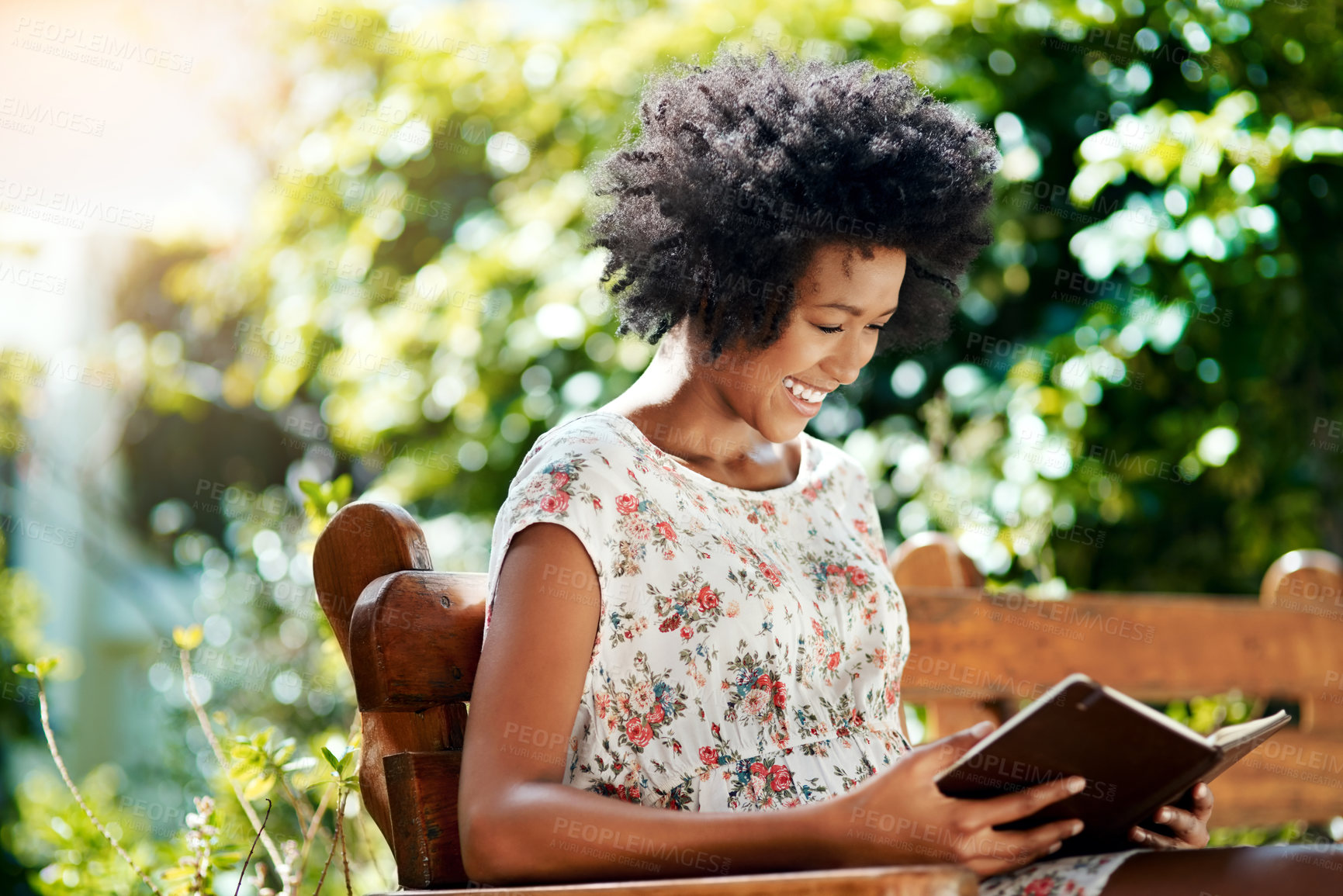 Buy stock photo Black woman, park and bench with book for read, literature and learning outdoors in nature. Smile, afro and relax in spring for peace, knowledge and education for female person on weekend or break