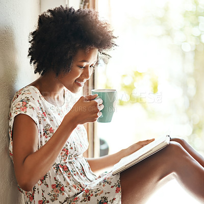 Buy stock photo Shot of a young woman relaxing with coffee and a book at home