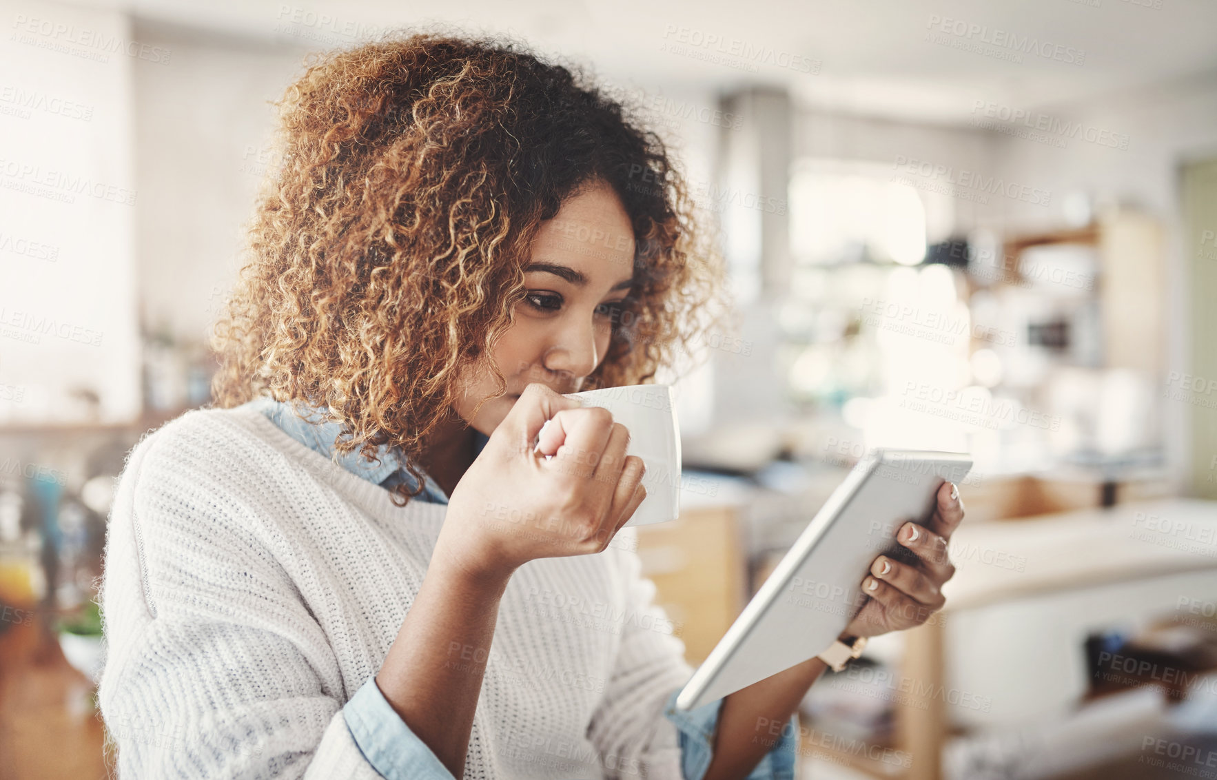 Buy stock photo Relaxed, happy and carefree woman drinking coffee and reading social media on a tablet at home. Enjoying a relaxing break on a quiet morning or weekend and streaming online or browsing the internet