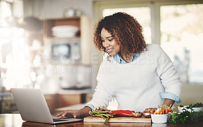 Buy stock photo Happy woman following an online recipe, cooking healthy food on her home kitchen table or counter. Smiling African American female preparing fresh ingredients for a wellness lifestyle meal.
