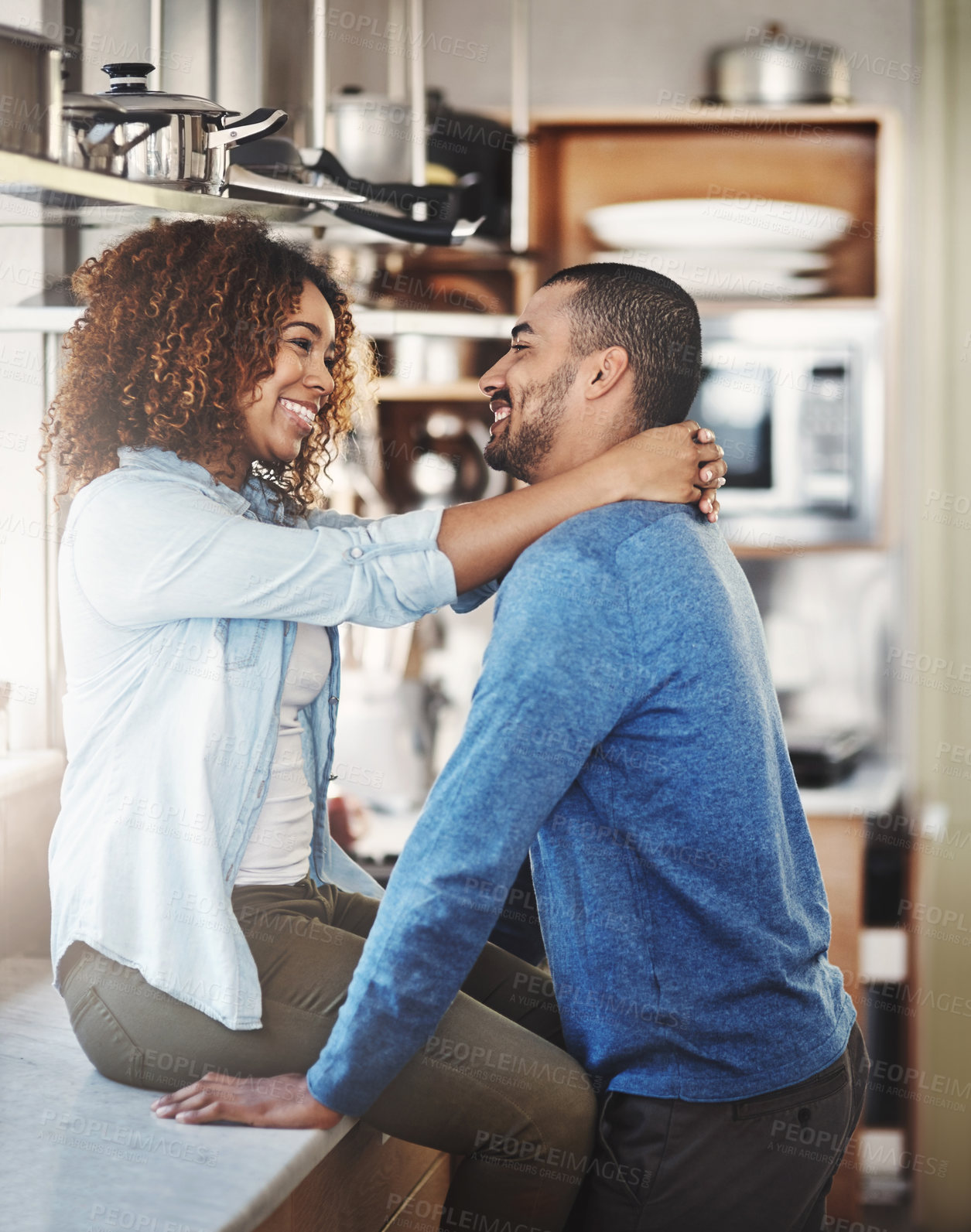 Buy stock photo Happy loving young couple having a romantic morning in the kitchen at home. Man and woman smiling in love and happiness and spending affectionate free time together in their kitchen