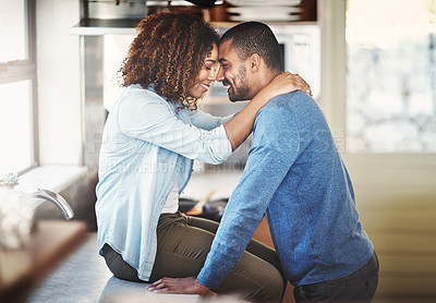 Buy stock photo Young happy couple hugging and having a romantic moment in a kitchen at home. Relaxed boyfriend and girlfriend talking while embracing and bonding, enjoying their time together in a new apartment 