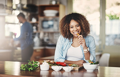 Buy stock photo Happy woman eating carrot vegetables while making healthy organic, fresh and nutrition filled food for dinner in the kitchen. Afro wife smiling while enjoying her vegetable diet before cooking a meal