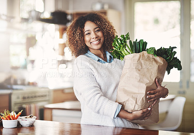 Buy stock photo Portrait of a happy young woman holding a bag full of healthy vegetables at home