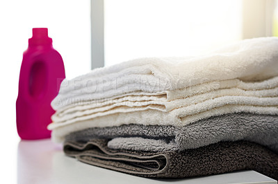 Buy stock photo Shot of a bottle of detergent alongside a pile of folded towels at home 