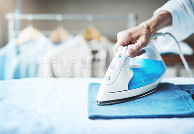 Buy stock photo Closeup shot of an unidentifiable woman ironing clothes at home
