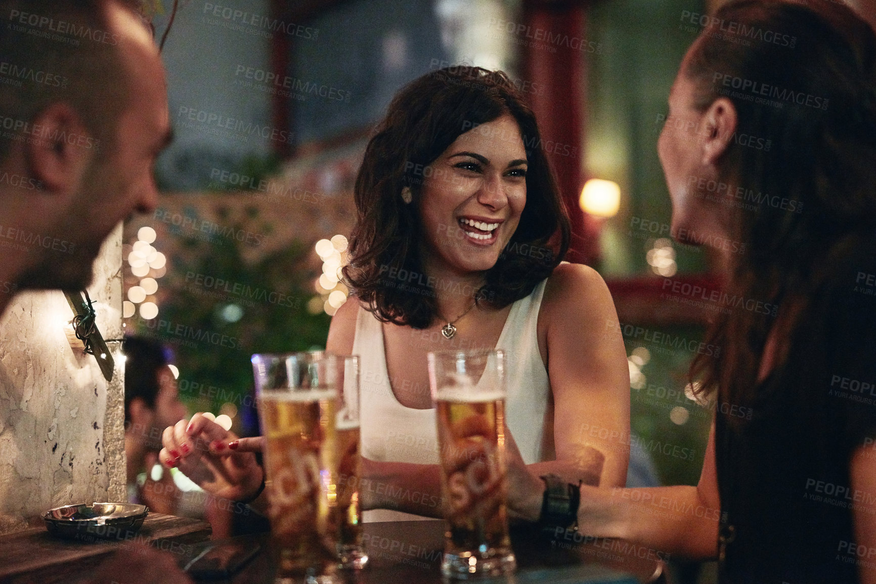 Buy stock photo Cropped shot of three friends having beers in a bar