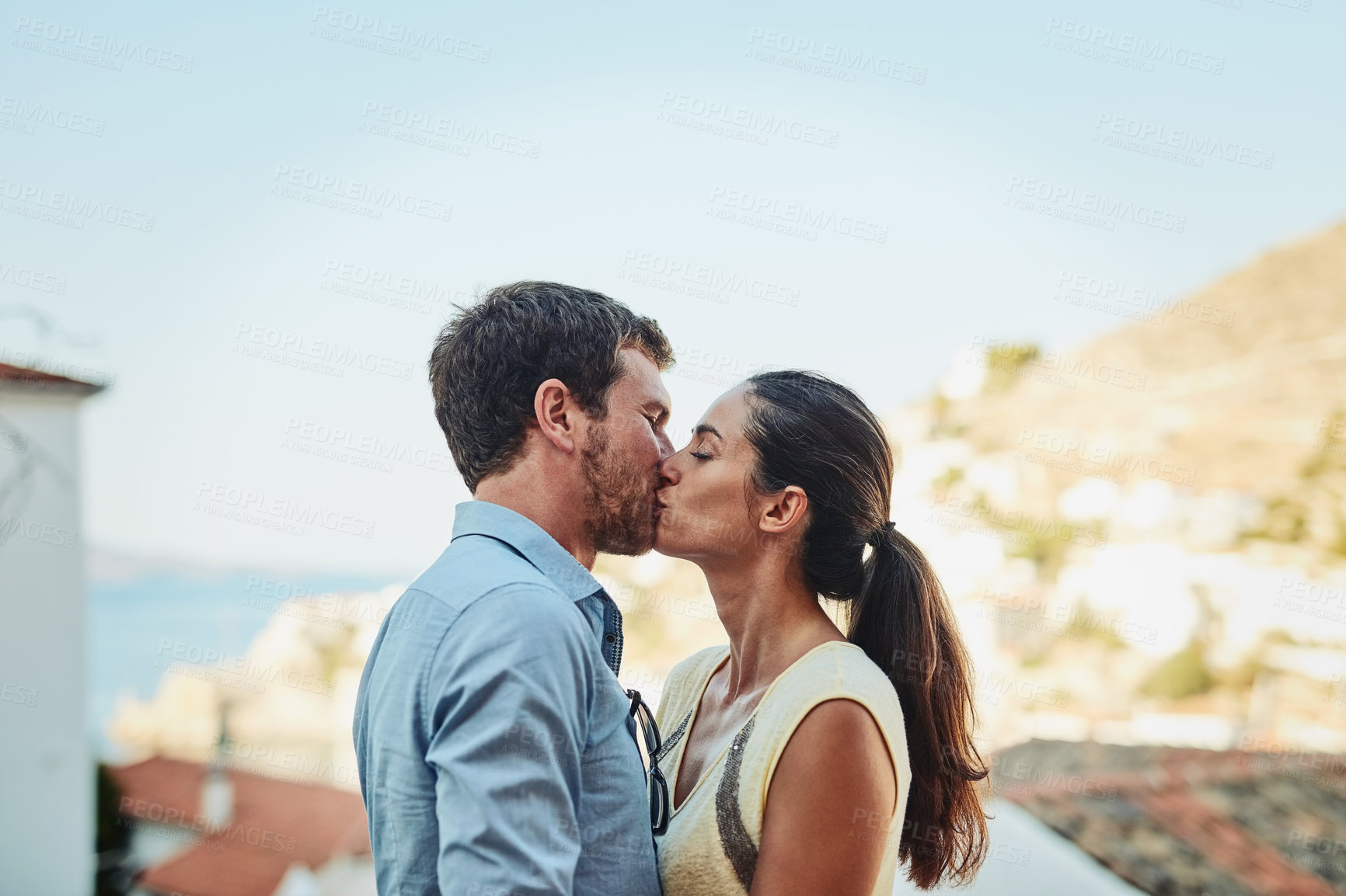 Buy stock photo Couple, kiss and rooftop in city on holiday, marriage commitment and travel to Greece. People, outdoor date and support for security in relationship, romance and terrace on honeymoon weekend trip