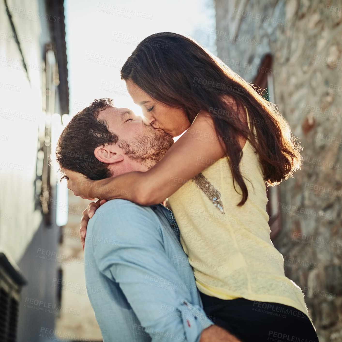 Buy stock photo Couple, kiss and carrying wife in city on holiday, marriage commitment and travel to Greece. People, outdoor and support for security in relationship, romance and together on honeymoon weekend trip