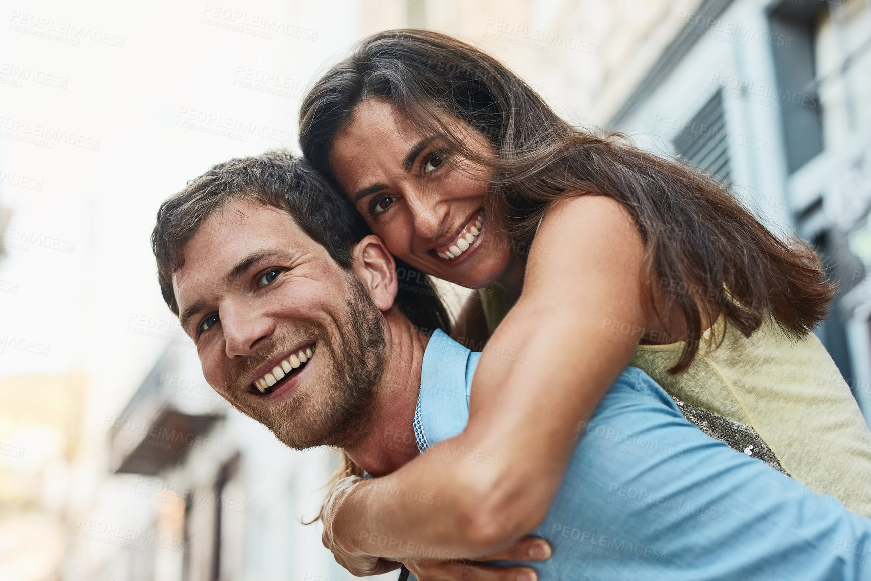 Buy stock photo Couple, portrait and piggyback in city on holiday, marriage commitment and travel to Greece. People, outdoor and support for security in relationship, adventure and play on honeymoon weekend trip