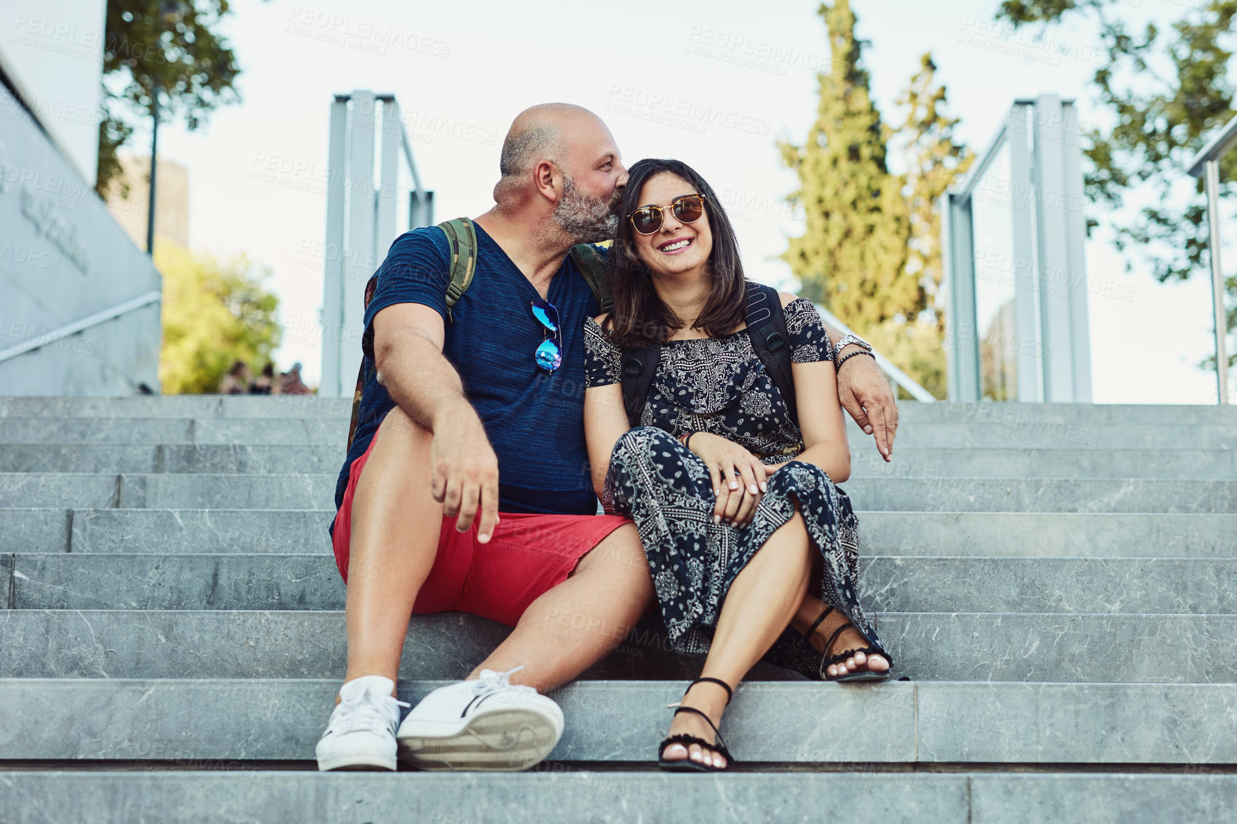 Buy stock photo Outdoor, couple and happy on stairs with kiss for fun, love and bonding in Spain. People, relationship and smile or satisfied outside with affection on break to relax, rest and chill on holiday