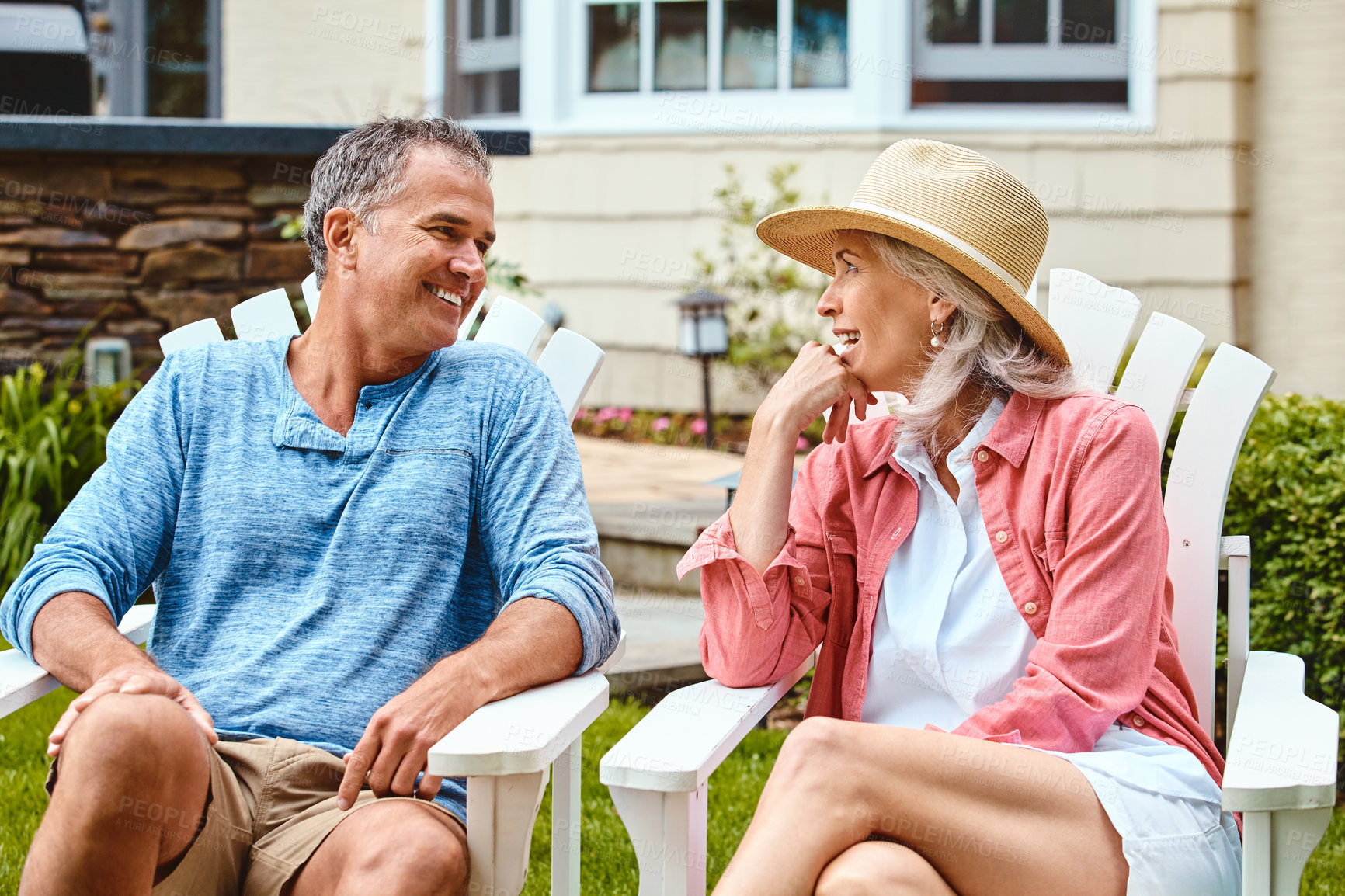 Buy stock photo Mature couple, lawn and relax on deck chair with funny conversation, bonding and care in summer at house. Man, woman and happy with laughing at comic memory, talk or chat on grass in backyard garden