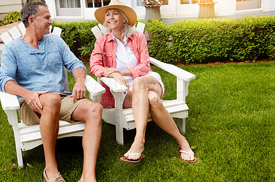 Buy stock photo Mature couple, garden and happy on chair with funny conversation, bonding and care in summer at house. Man, woman and talk with laughing at joke memory, relax and chat on grass in home backyard