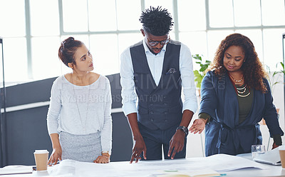 Buy stock photo Cropped shot of a team of professionals working on blueprints in an office