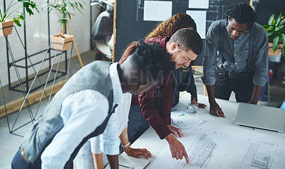 Buy stock photo Cropped shot of a team of professionals working on blueprints in an office