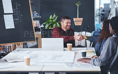 Buy stock photo Cropped shot of two creative businesspeople shaking hands during a meeting in their office