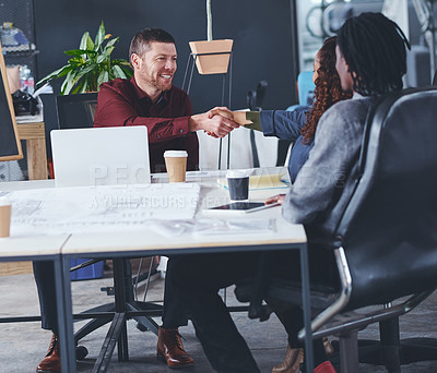 Buy stock photo Cropped shot of two creative businesspeople shaking hands during a meeting in their office