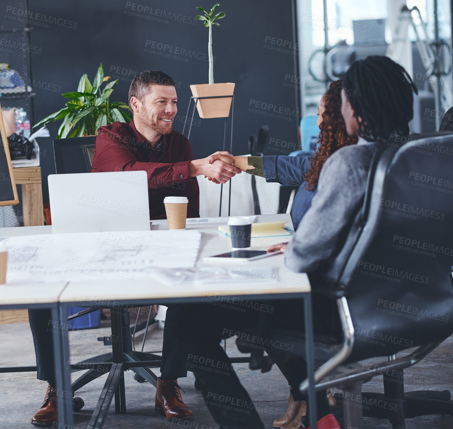 Buy stock photo Cropped shot of two creative businesspeople shaking hands during a meeting in their office