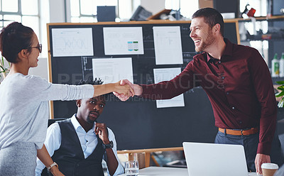 Buy stock photo Cropped shot of two creative businesspeople shaking hands during a meeting in their office