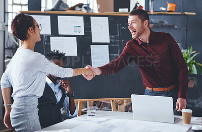 Buy stock photo Cropped shot of two creative businesspeople shaking hands during a meeting in their office