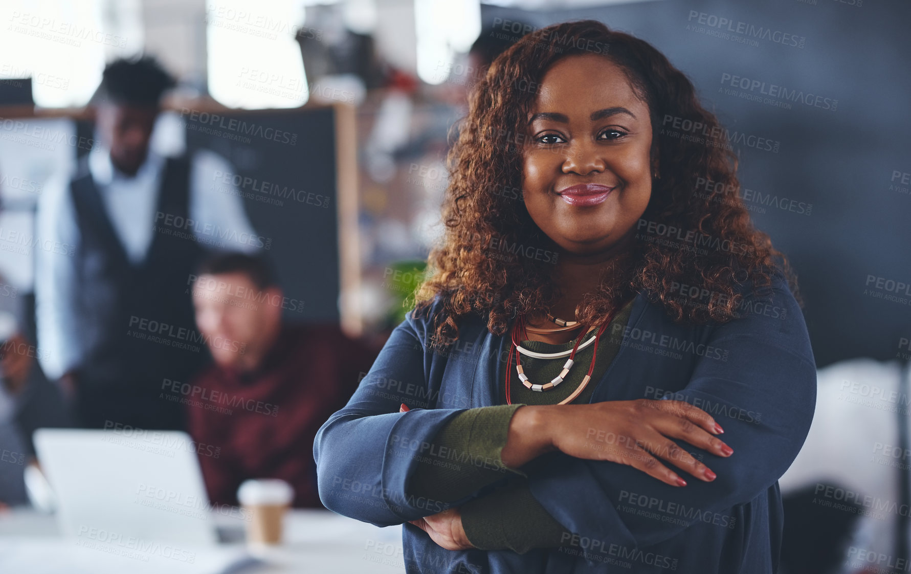 Buy stock photo Cropped portrait of an attractive young businesswoman standing with her arms folded with her colleagues in the background