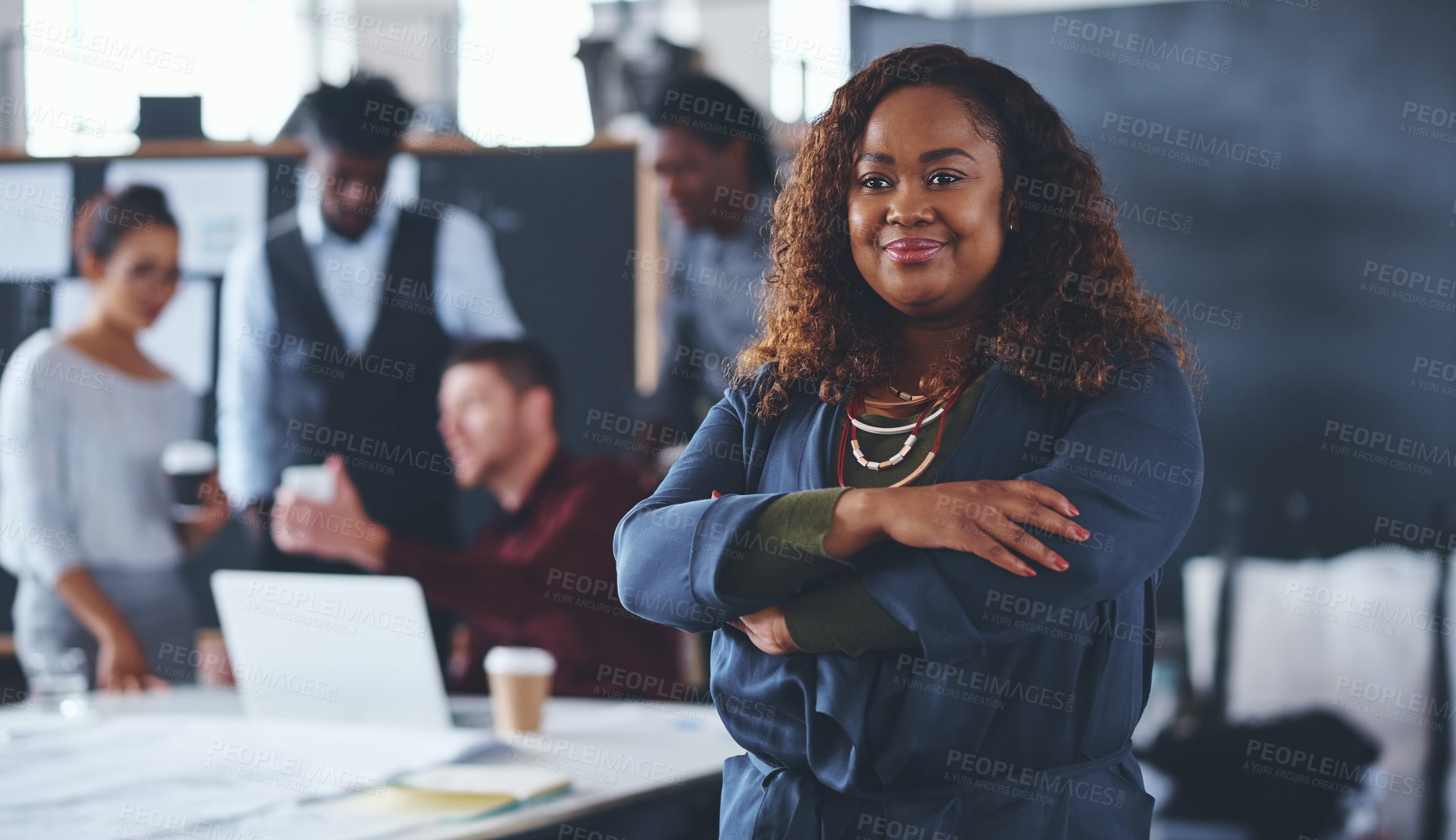 Buy stock photo Cropped portrait of an attractive young businesswoman standing with her arms folded with her colleagues in the background