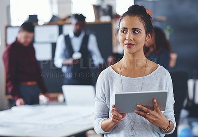 Buy stock photo Cropped shot of an attractive young businesswoman using a tablet in the office with her colleagues in the background