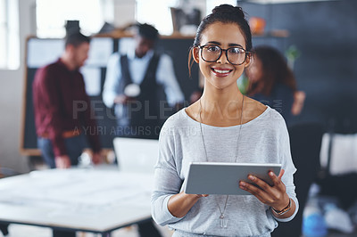Buy stock photo Cropped portrait of an attractive young businesswoman using a tablet in the office with her colleagues in the background