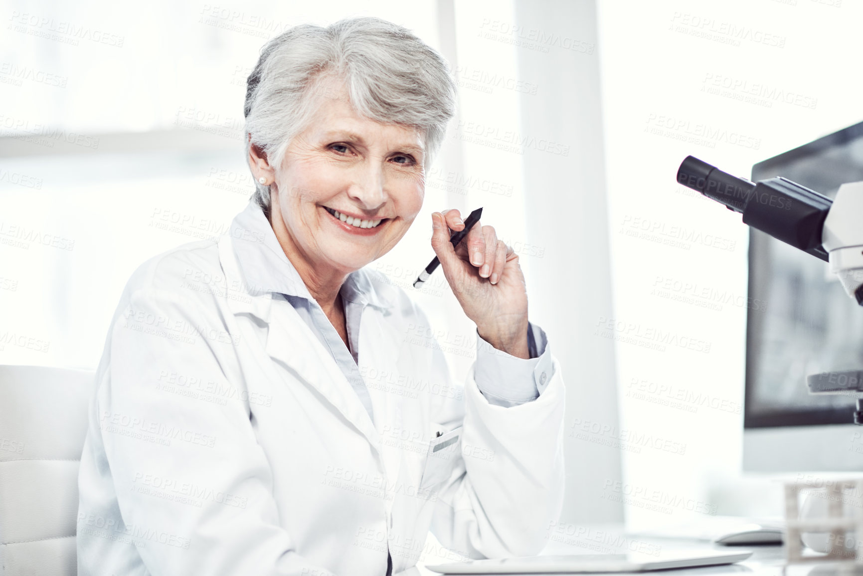 Buy stock photo Portrait of a cheerful elderly female scientist making notes while looking at the camera and smiling in a laboratory
