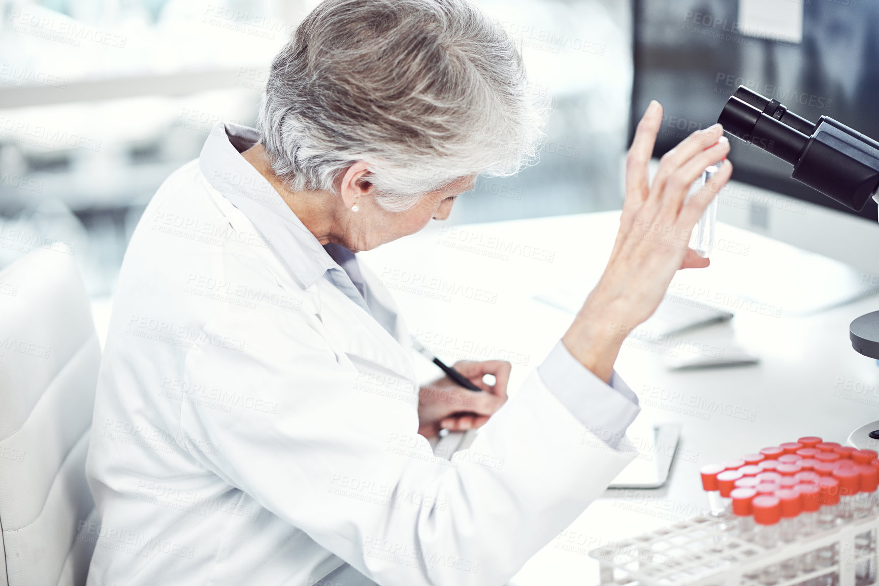 Buy stock photo Shot of a focused elderly female scientist holding up a test tube and examining it inside of a laboratory