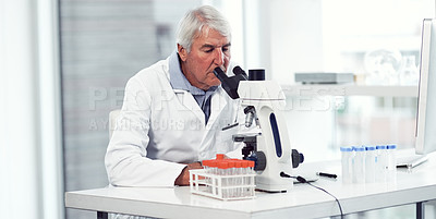 Buy stock photo Shot of a focused elderly male scientist looking through a microscope while being seated inside of a laboratory