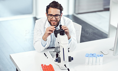 Buy stock photo Shot of a cheerful young male scientist looking through a microscope inside of a laboratory