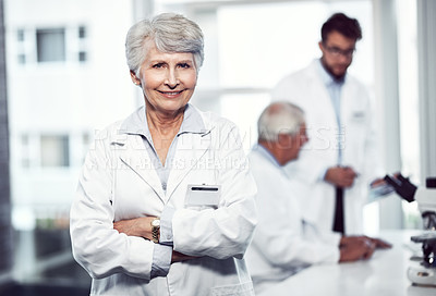 Buy stock photo Portrait of a cheerful elderly female scientist standing with arms folded and looking into the camera inside a laboratory
