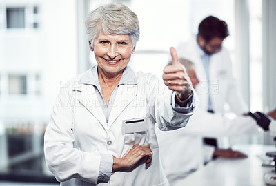 Buy stock photo Portrait of a cheerful elderly female scientist showing thumbs up while looking into the camera inside a laboratory