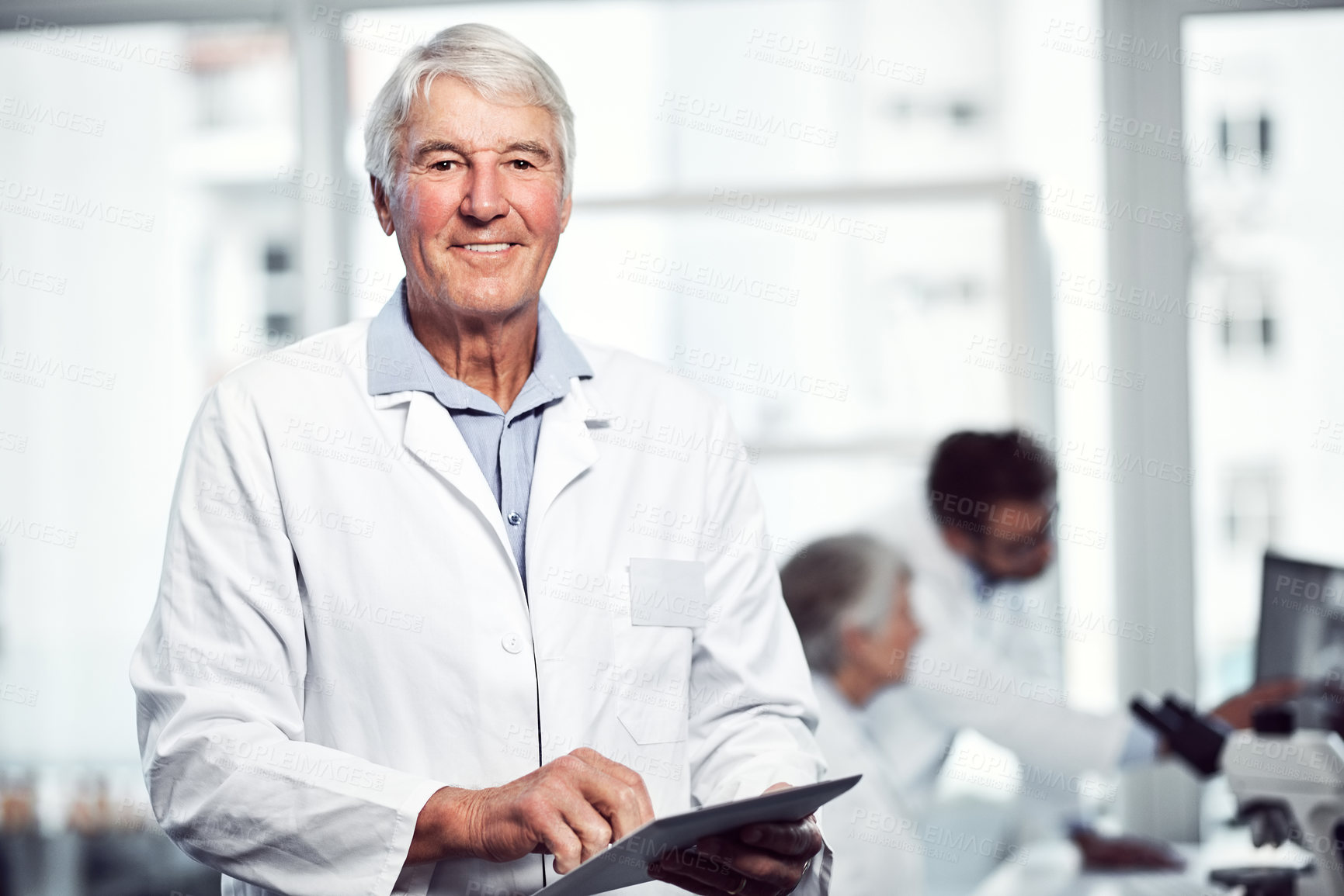 Buy stock photo Portrait of cheerful elderly male scientist using a digital tablet while looking into the camera inside a laboratory