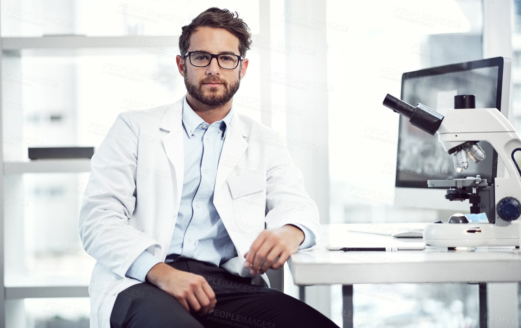 Buy stock photo Shot of a confident young male scientist looking into the camera while being seated inside of a laboratory