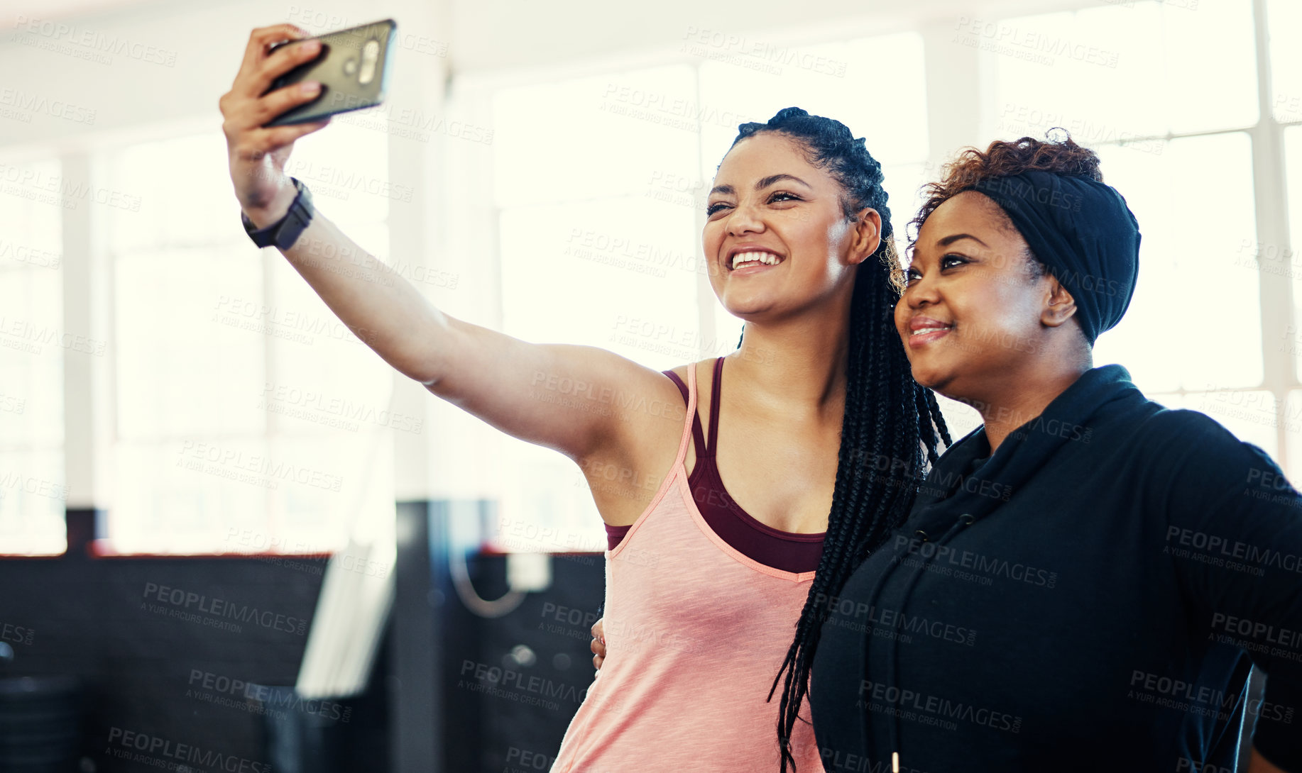 Buy stock photo Shot of two cheerful young women taking a self portrait together before a workout session in a gym
