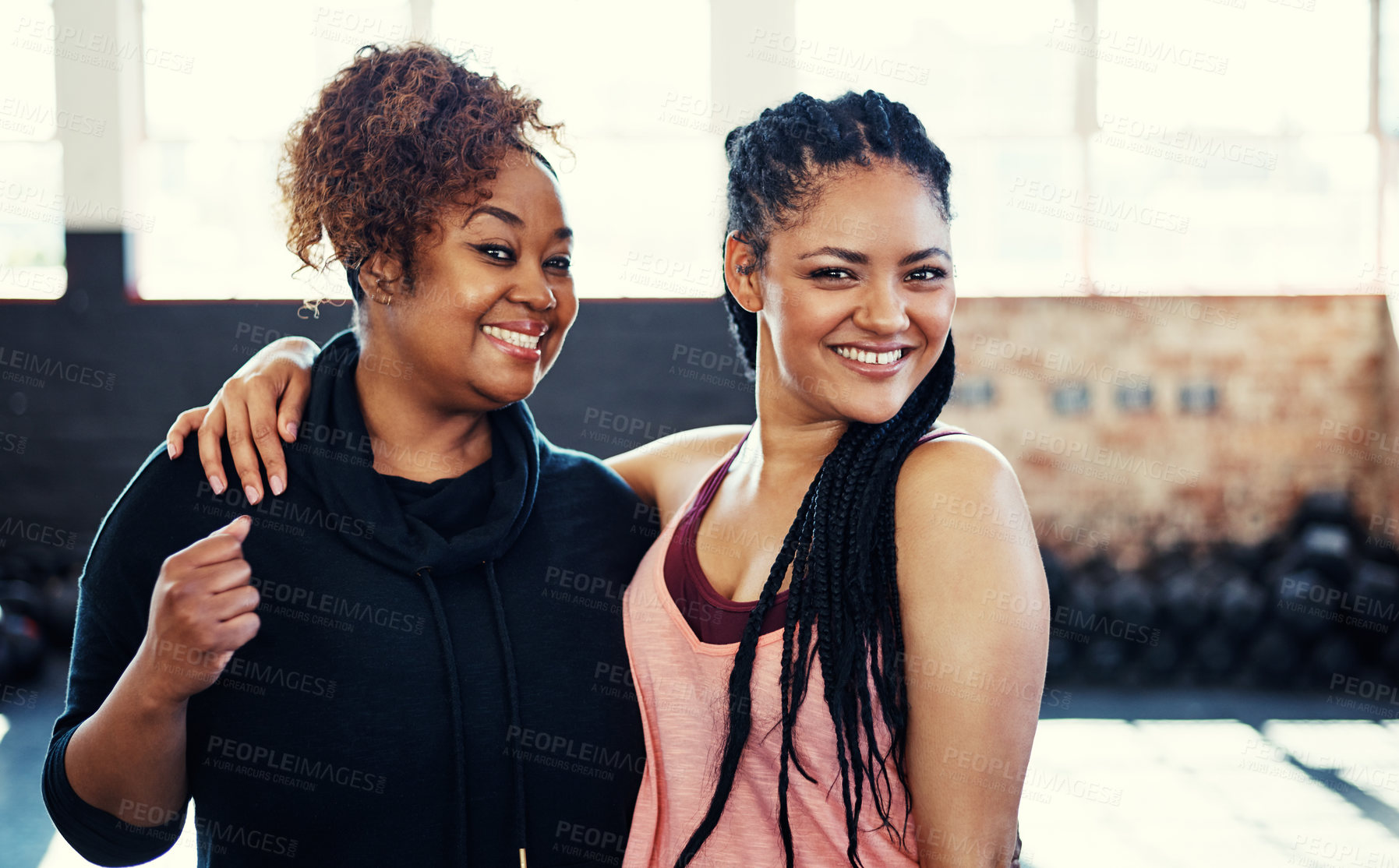 Buy stock photo Portrait of two cheerful young women having a conversation while looking into the camera before a workout session in a gym