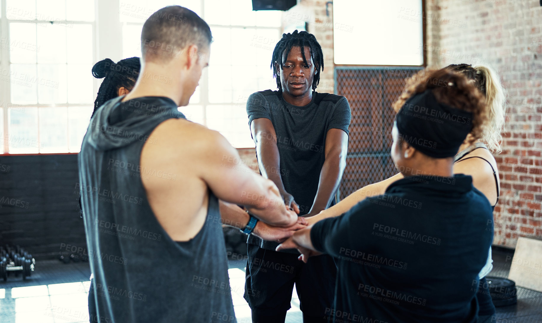Buy stock photo Shot of a focused young group of people forming a huddle together before a workout session in a gym