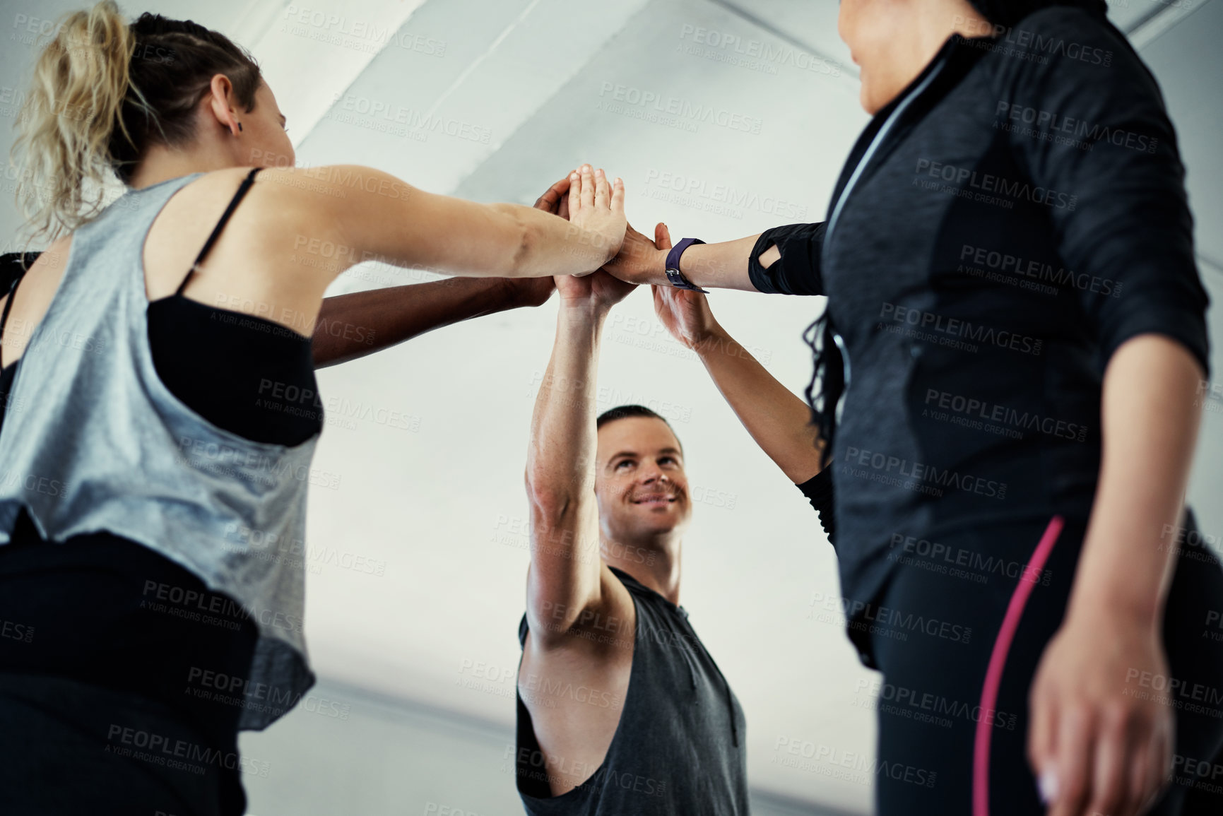 Buy stock photo Shot of a cheerful young group of people forming a huddle together before a workout session in a gym