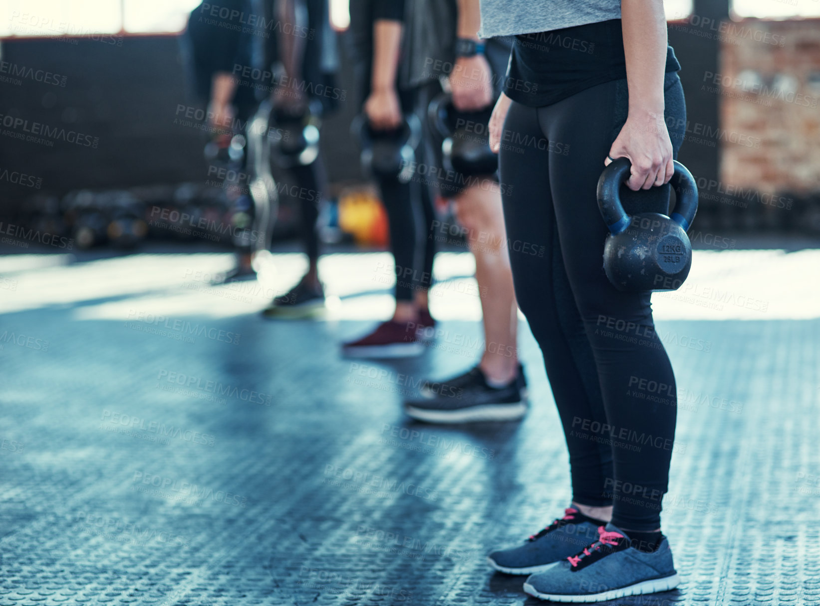 Buy stock photo Shot of a group unrecognizable people standing in a row doing training with weights in a gym