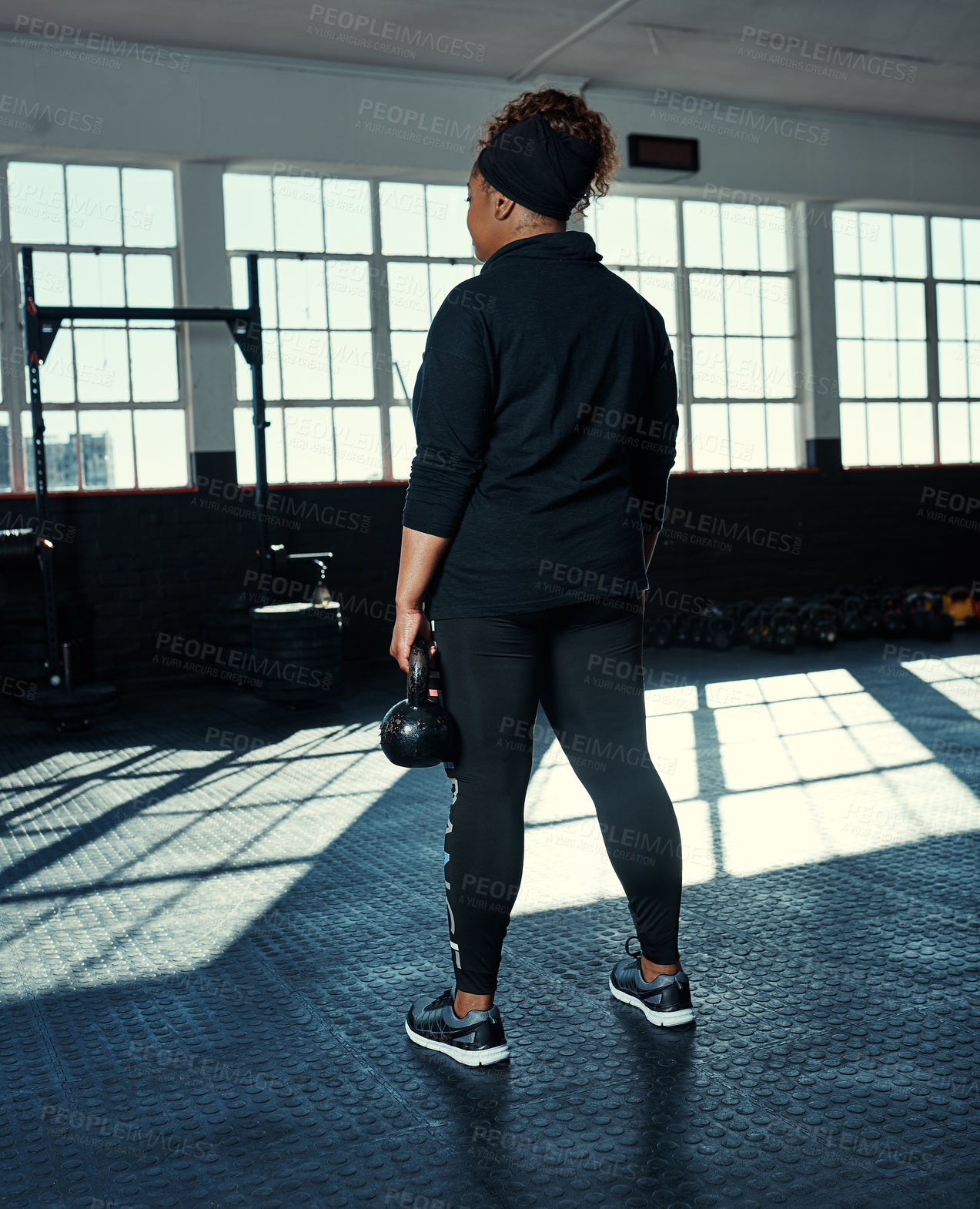 Buy stock photo Rearview shot of an unrecognizable woman lifting kettlebells in a gym