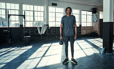 Buy stock photo Shot of a young man lifting kettlebells in a gym