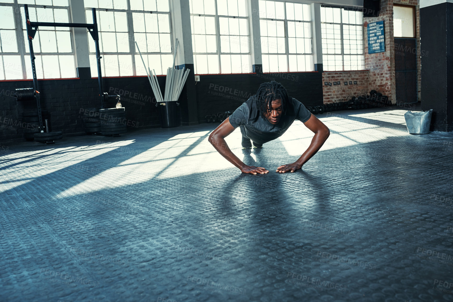 Buy stock photo Shot of a young man doing push ups in a gym