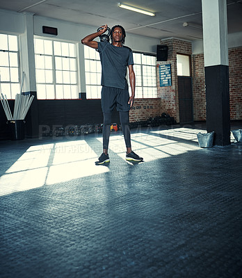 Buy stock photo Shot of a young man lifting kettlebells in a gym