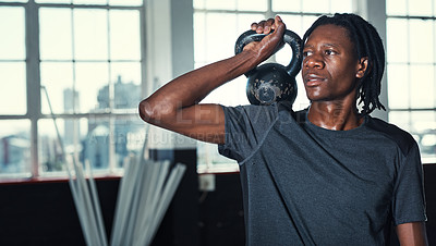 Buy stock photo Shot of a young man lifting kettlebells in a gym