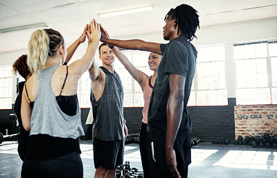 Buy stock photo Shot of a cheerful young group of people forming a huddle together before a workout session in a gym
