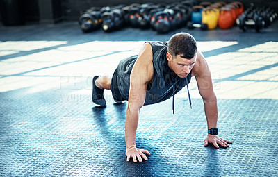 Buy stock photo Shot of a young man doing push ups in a gym