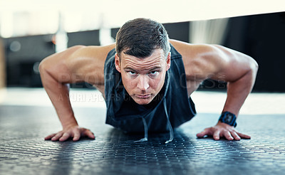 Buy stock photo Shot of a young man doing push ups in a gym