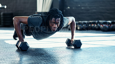 Buy stock photo Shot of a young man doing push ups with dumbbells in a gym